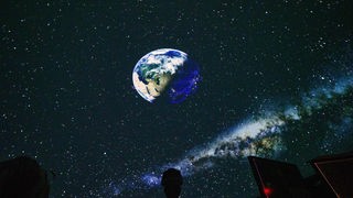 In der Projektion eines Planetariums ist die Erde aus der Sicht aus dem Weltall zu sehen.